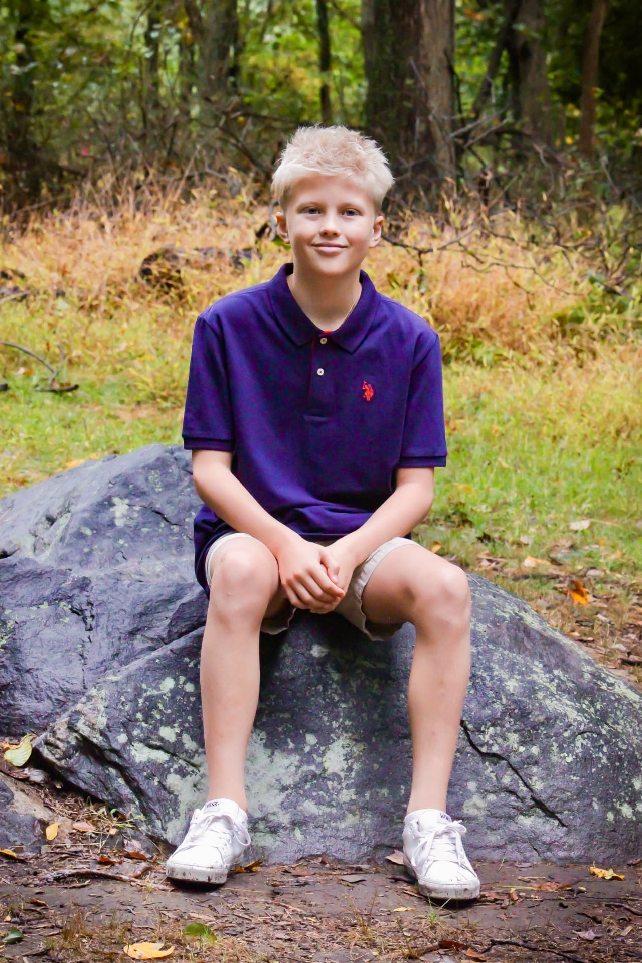 Hamish seated on a rock in a wooded area