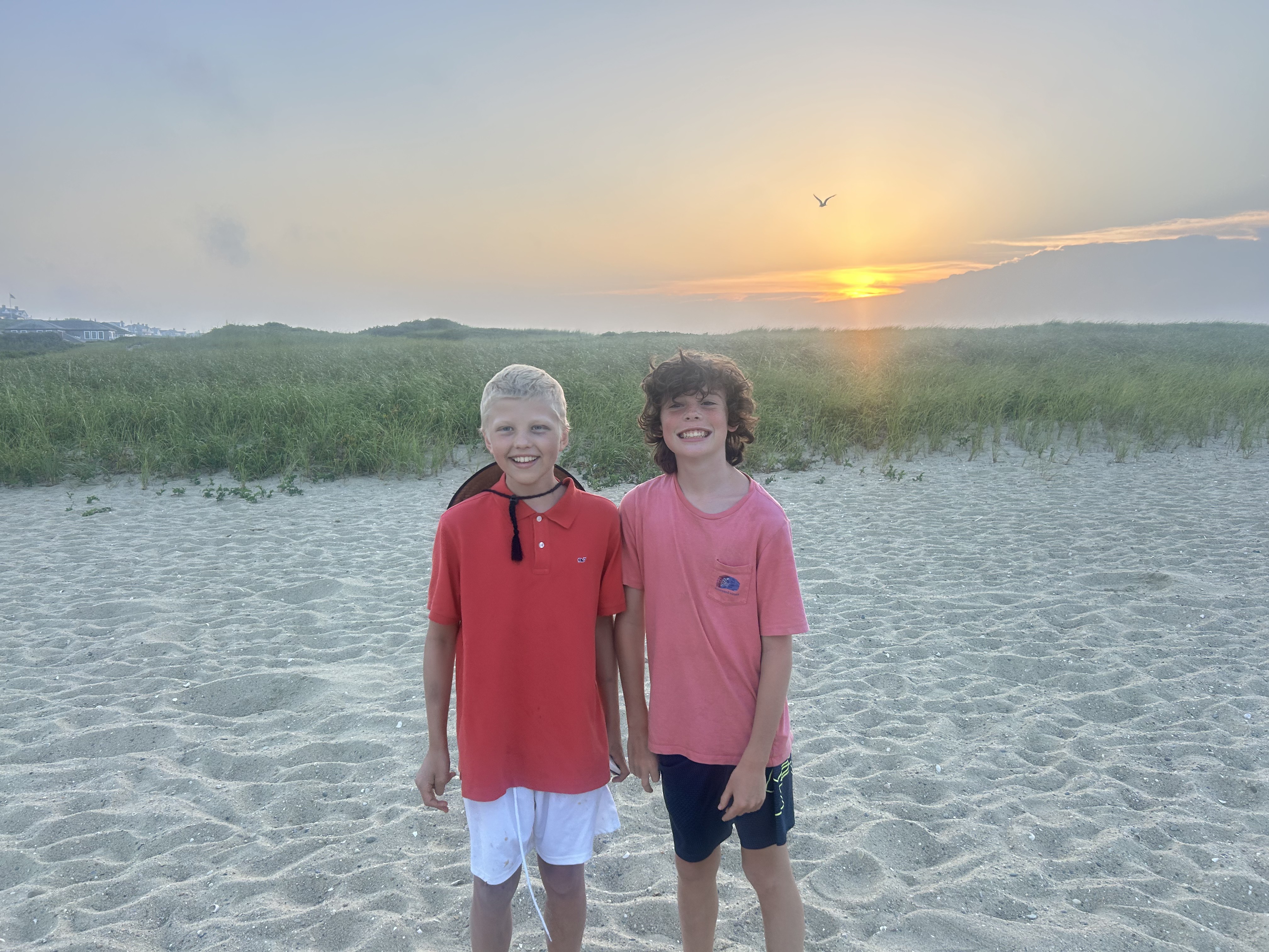 Hamish standing with a friend on a beach at sunset