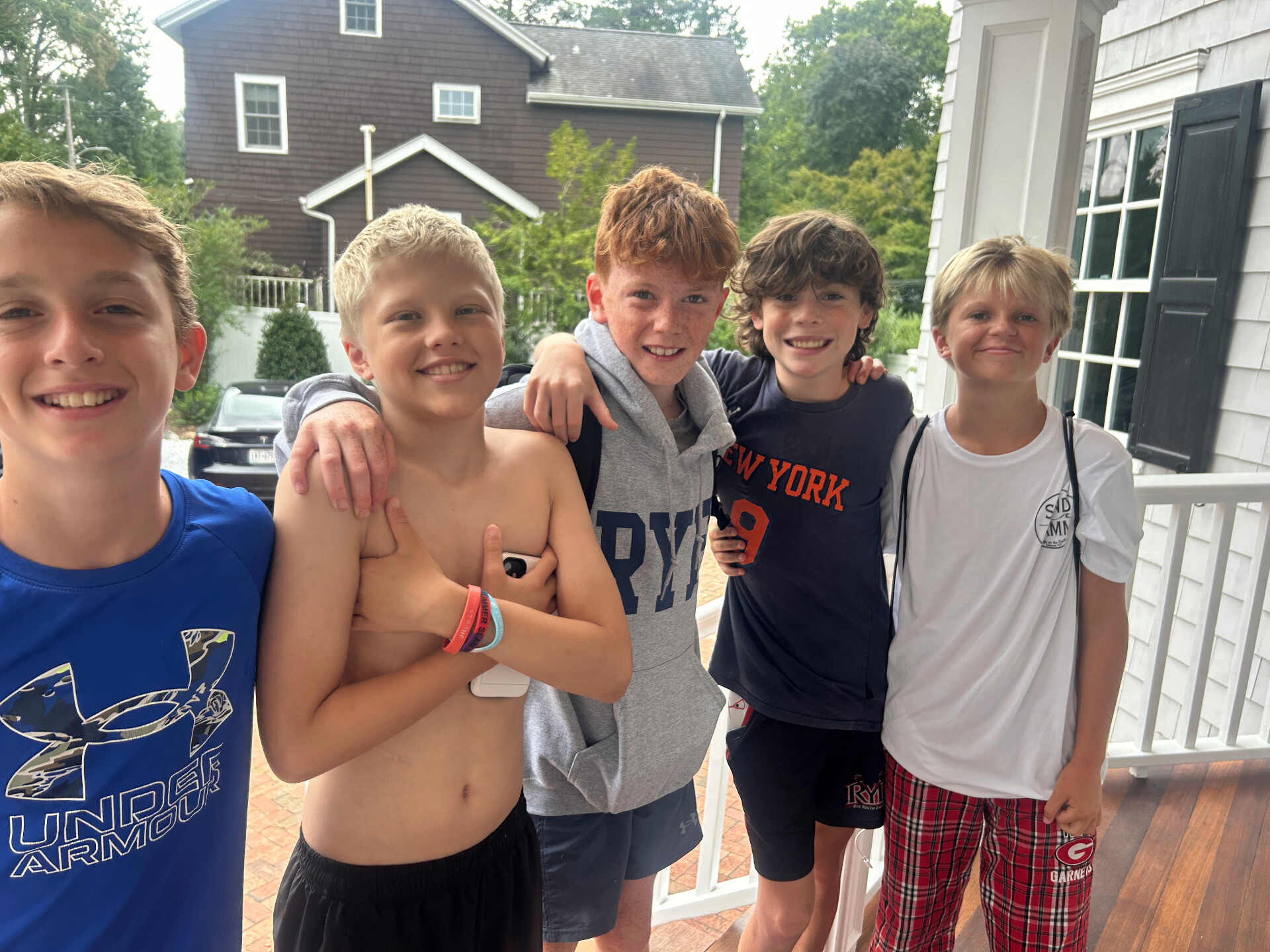 Hamish smiling with four friends on a porch