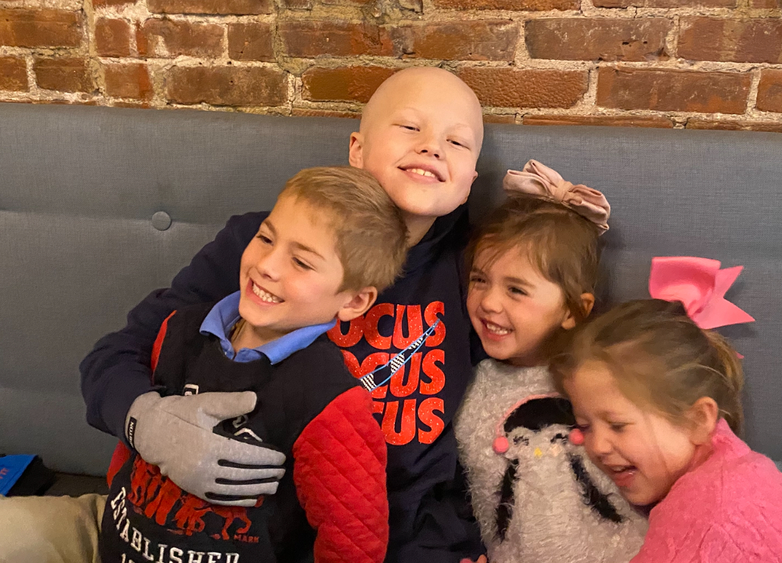 Hamish sitting closely with three children on a couch